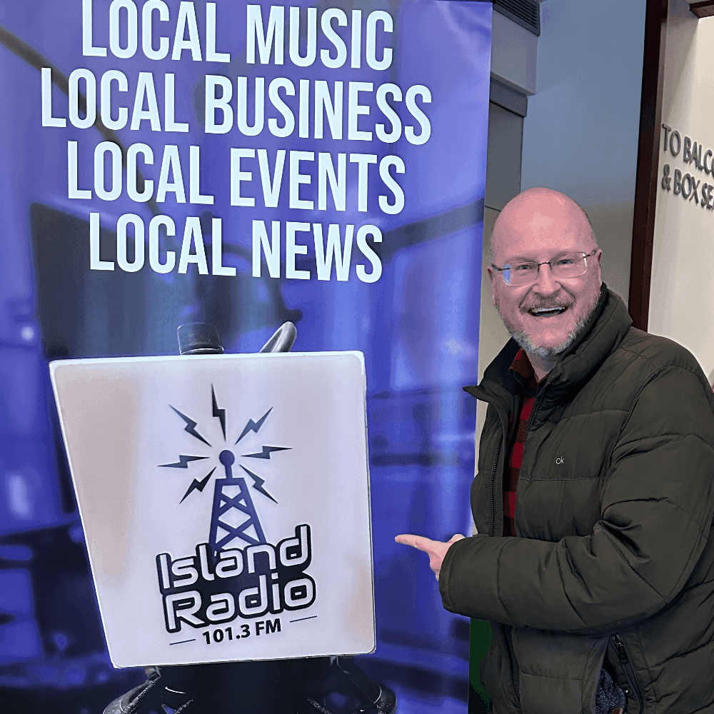 Island Radio volunteer holding phone showing donation page
